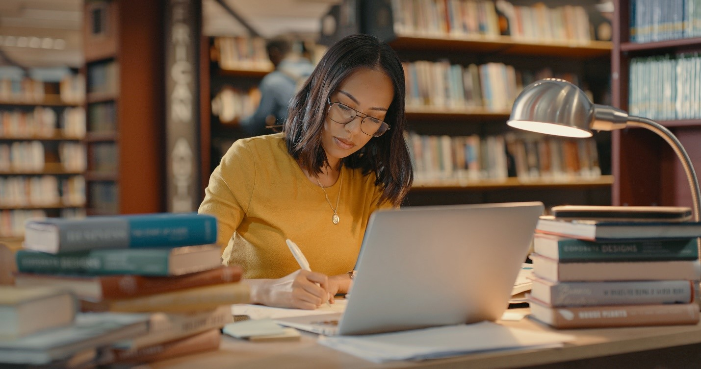 Publishing professional working with books and a laptop in a library